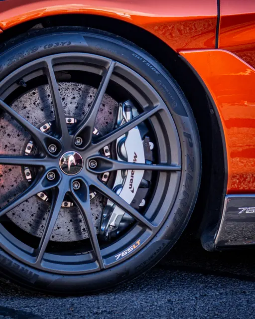 Close detail of an orange McLaren wheel, tyre and brake caliper