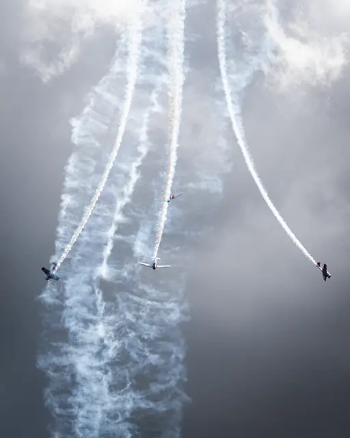 Aerobatic aircraft separating through dramatic white smoke trails