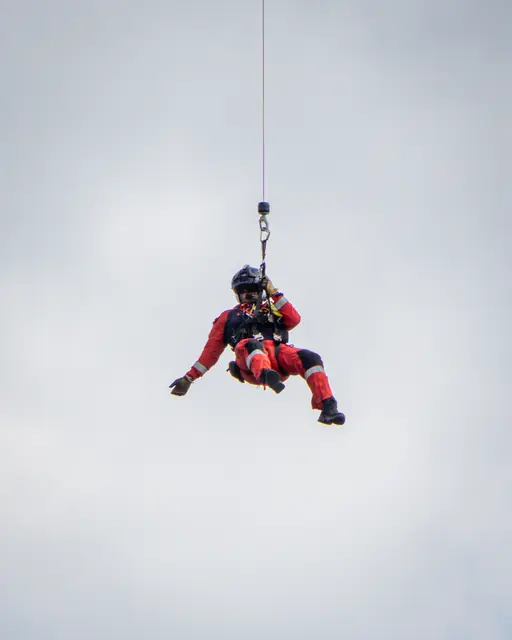 Rescue crew member suspended from a helicopter winch cable