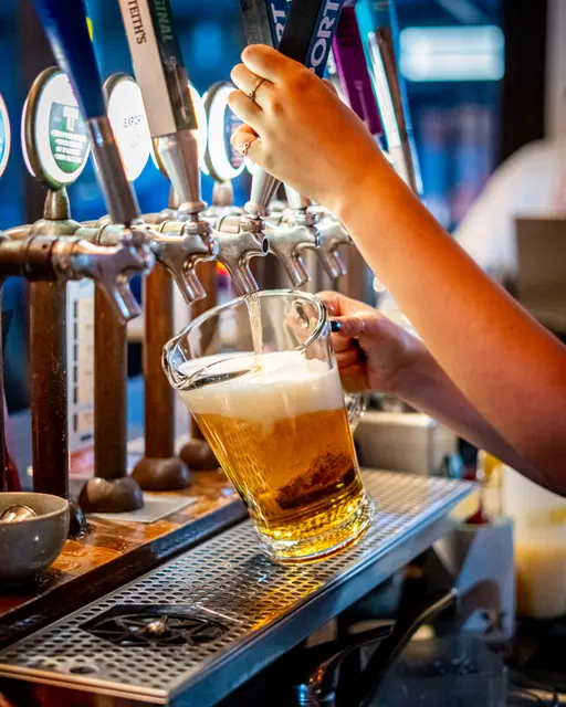 Bartender pouring a beer from a row of taps