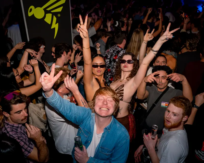 Friends raising their arms in a nightclub crowd