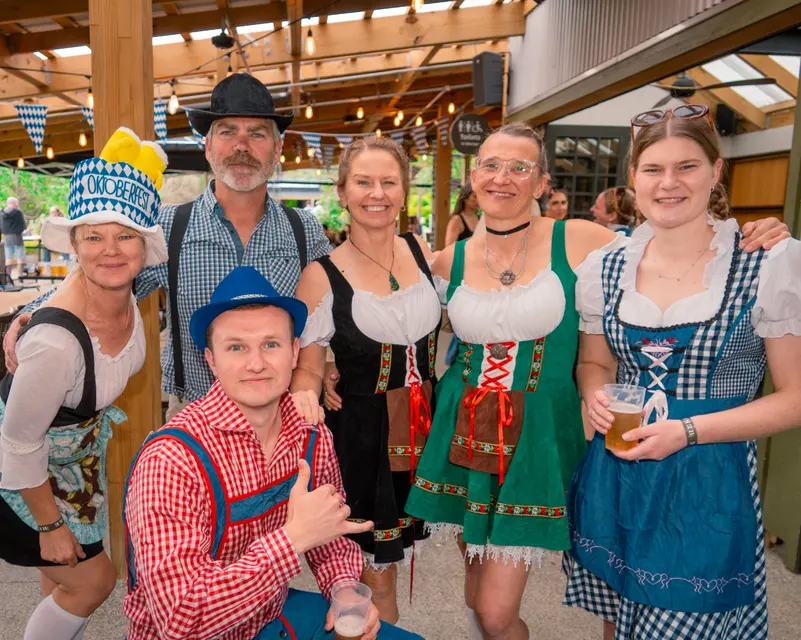 Oktoberfest guests in traditional clothing posing together at a venue