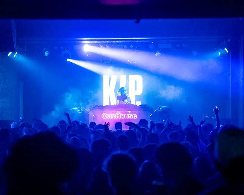 Blue stage lighting above a packed indoor audience