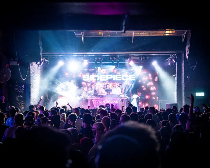 Indoor audience facing a brightly illuminated stage