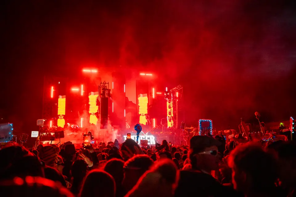 Outdoor festival audience facing a red illuminated stage