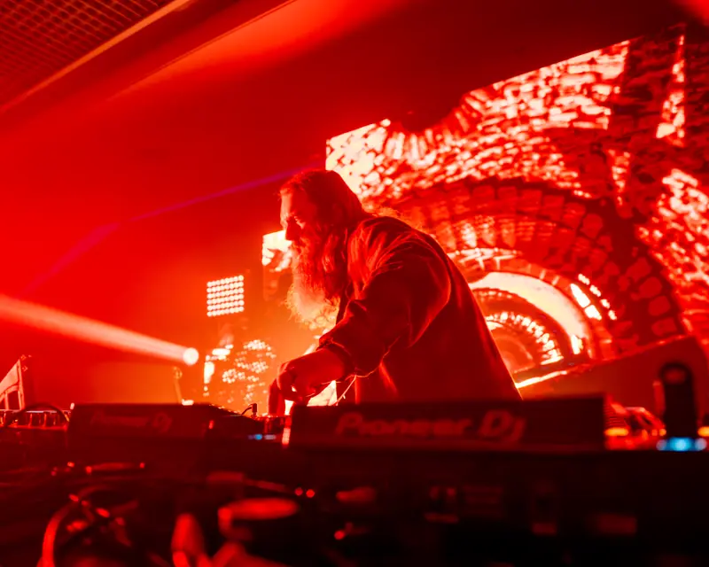 DJ silhouetted in red light in front of a large LED screen