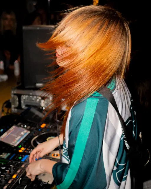 DJ with bright orange hair turning at the mixer