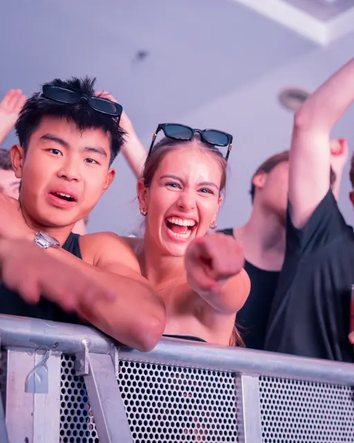 Two smiling guests leaning over a crowd barrier
