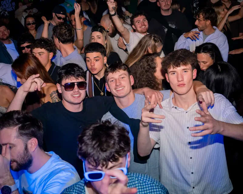 Three friends posing together in a nightclub crowd