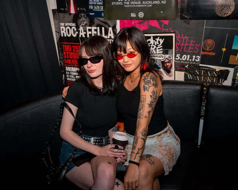 Two guests wearing sunglasses seated together in a booth