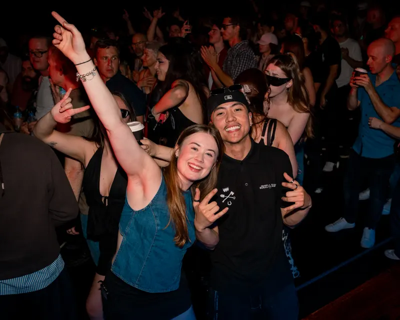 Two smiling guests posing in a busy crowd