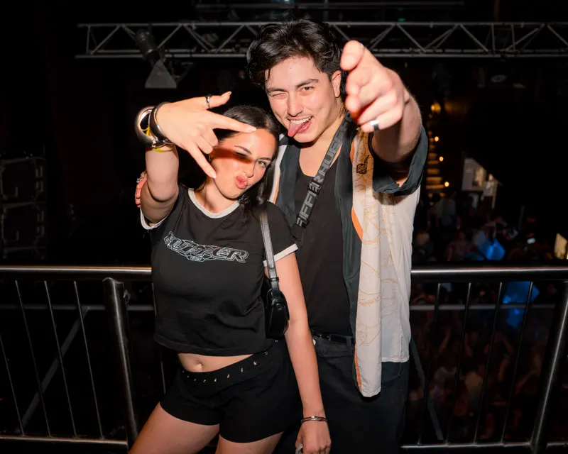 Two guests gesturing towards the camera inside a venue