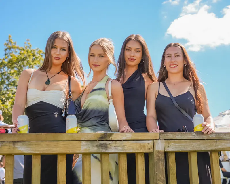 Four guests posing outdoors beneath a blue sky