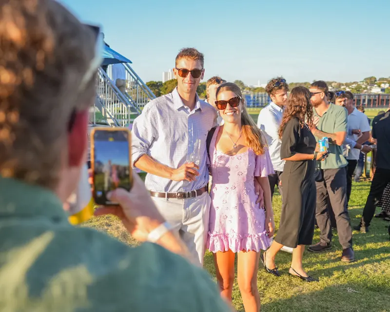Couple posing for a phone photograph at an outdoor gathering