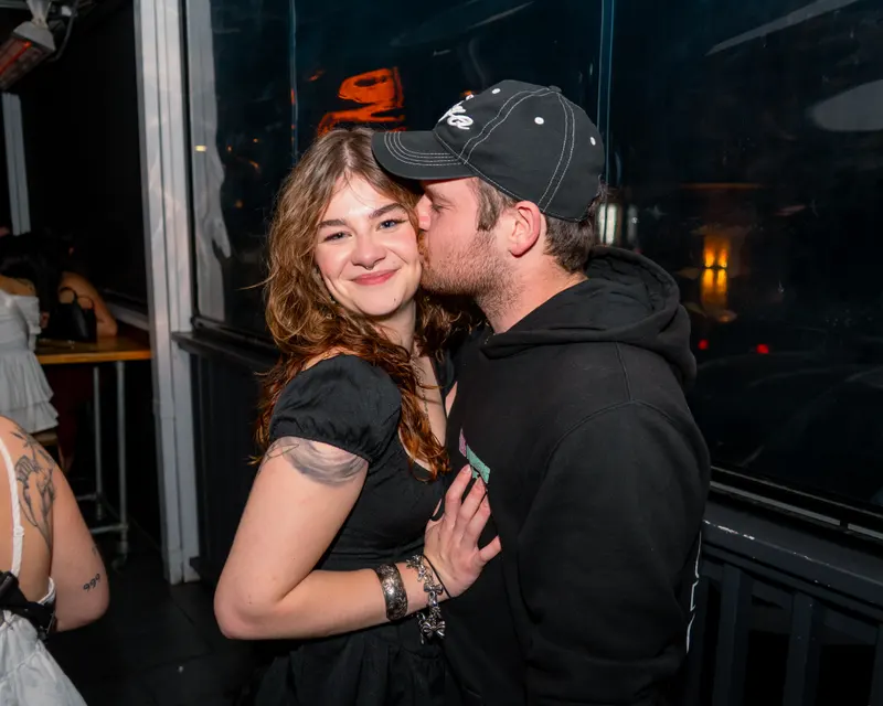 Couple sharing a kiss on the cheek at a bar