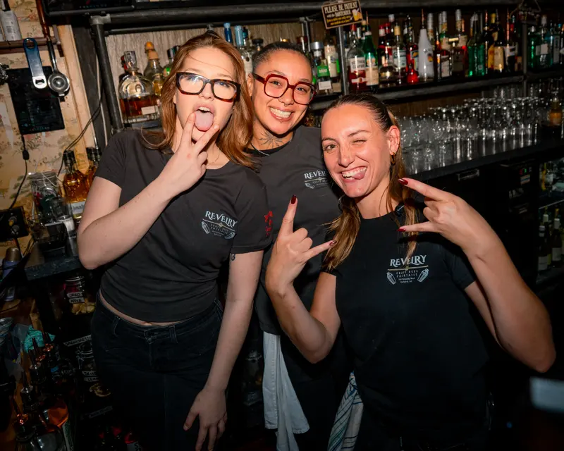 Three bar staff posing together behind the bar